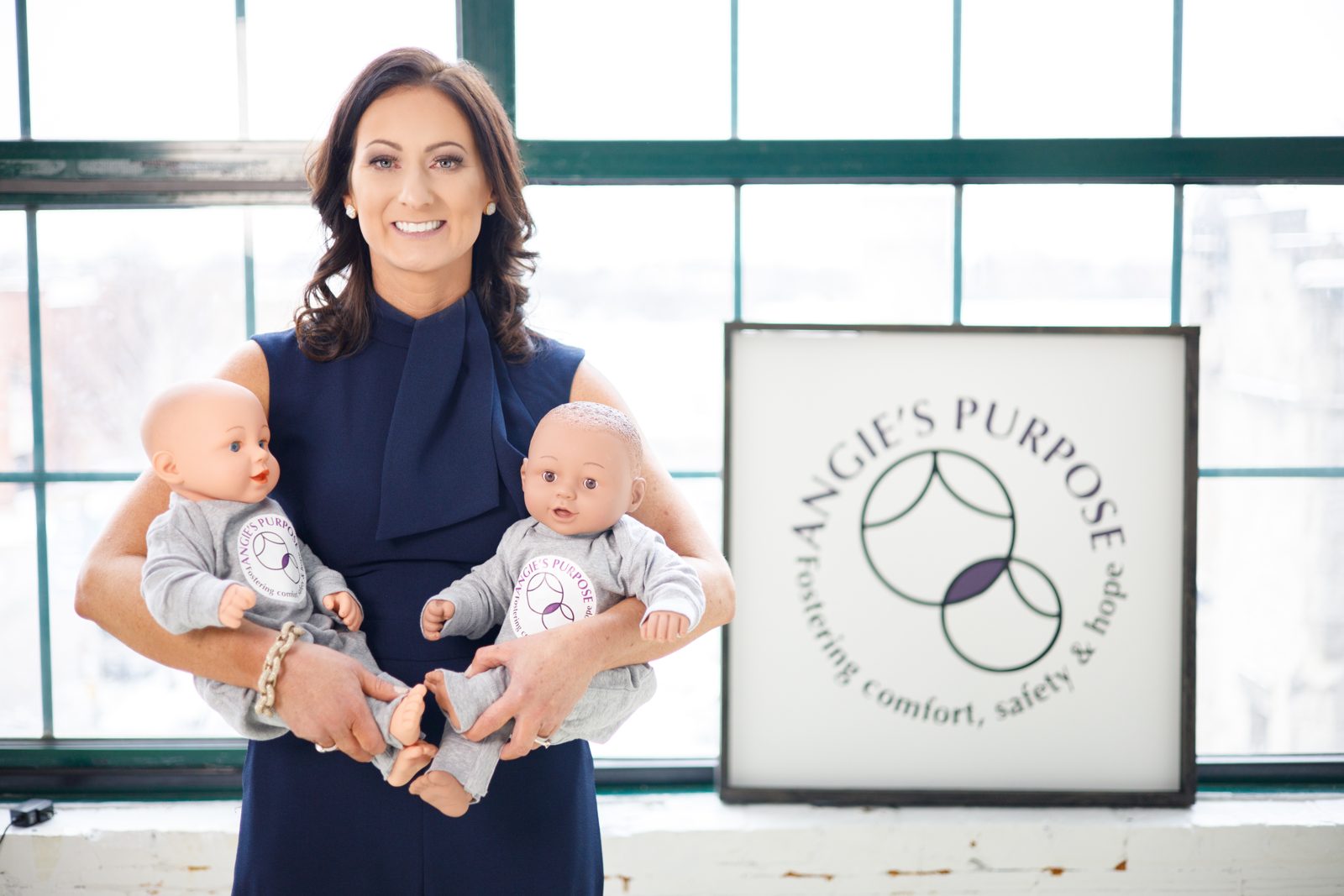 Angie Filipiak holding two therapeutic dolls beside the Angie’s Purpose logo